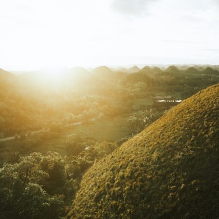 the sun shines through the clouds over the hills